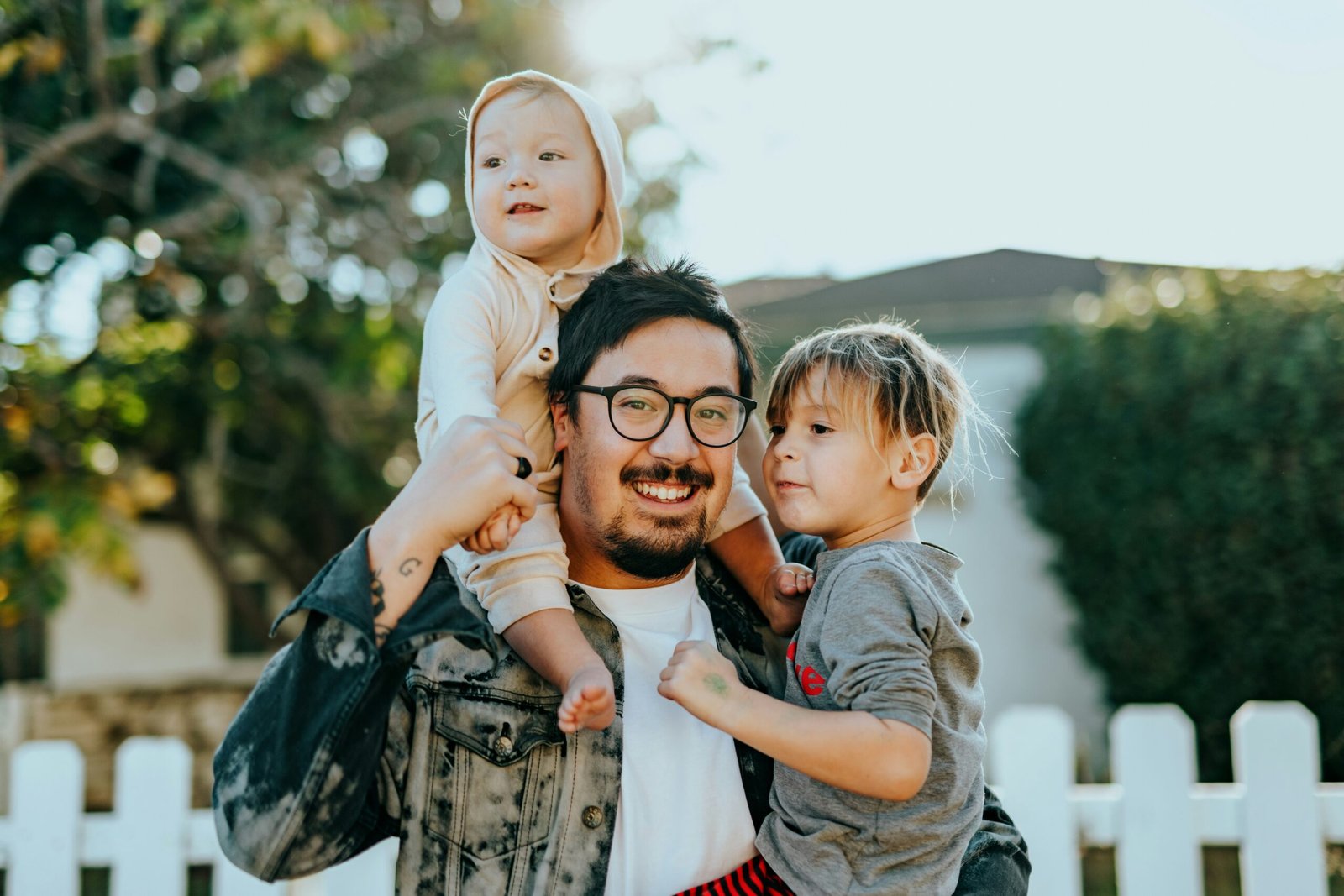 A parent smiling with two children outside