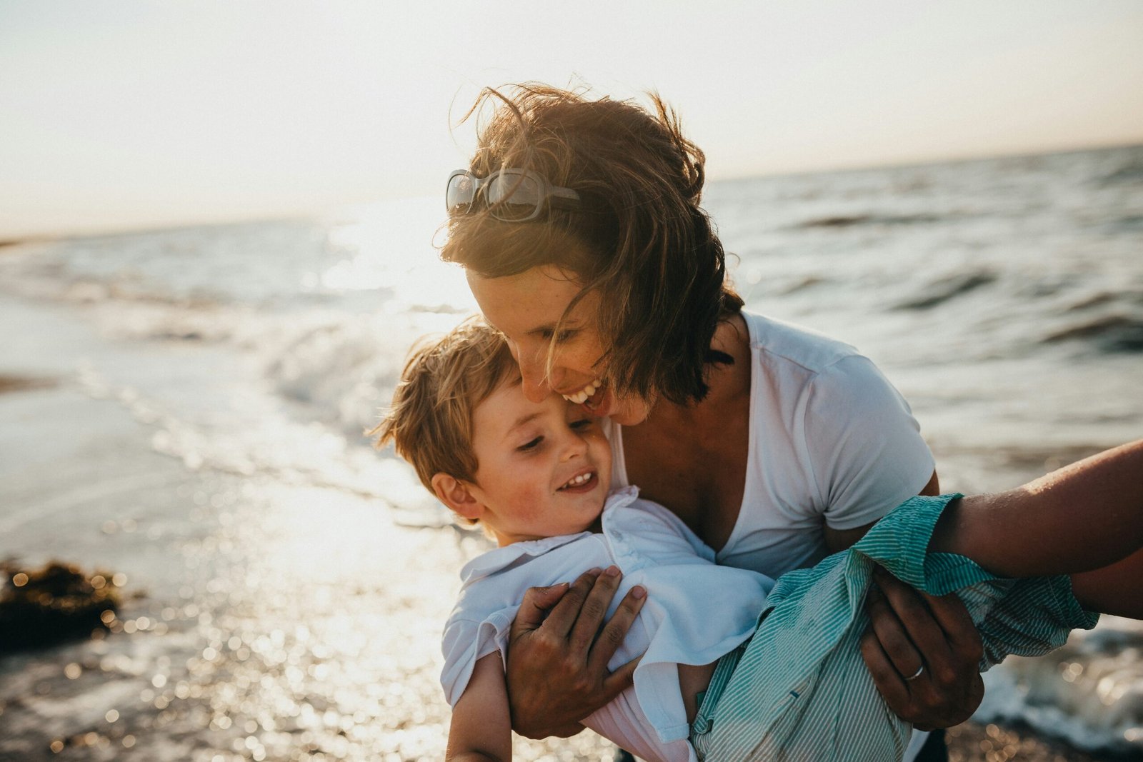 A parent and child laughing by the sea