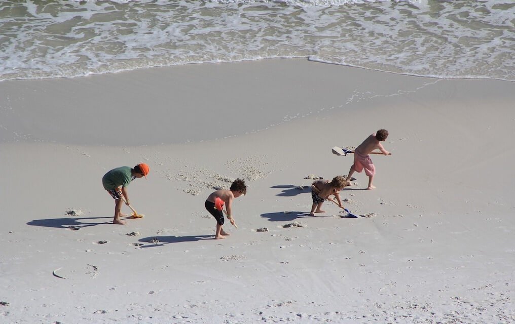Kids digging in the sand for things to do at the beach